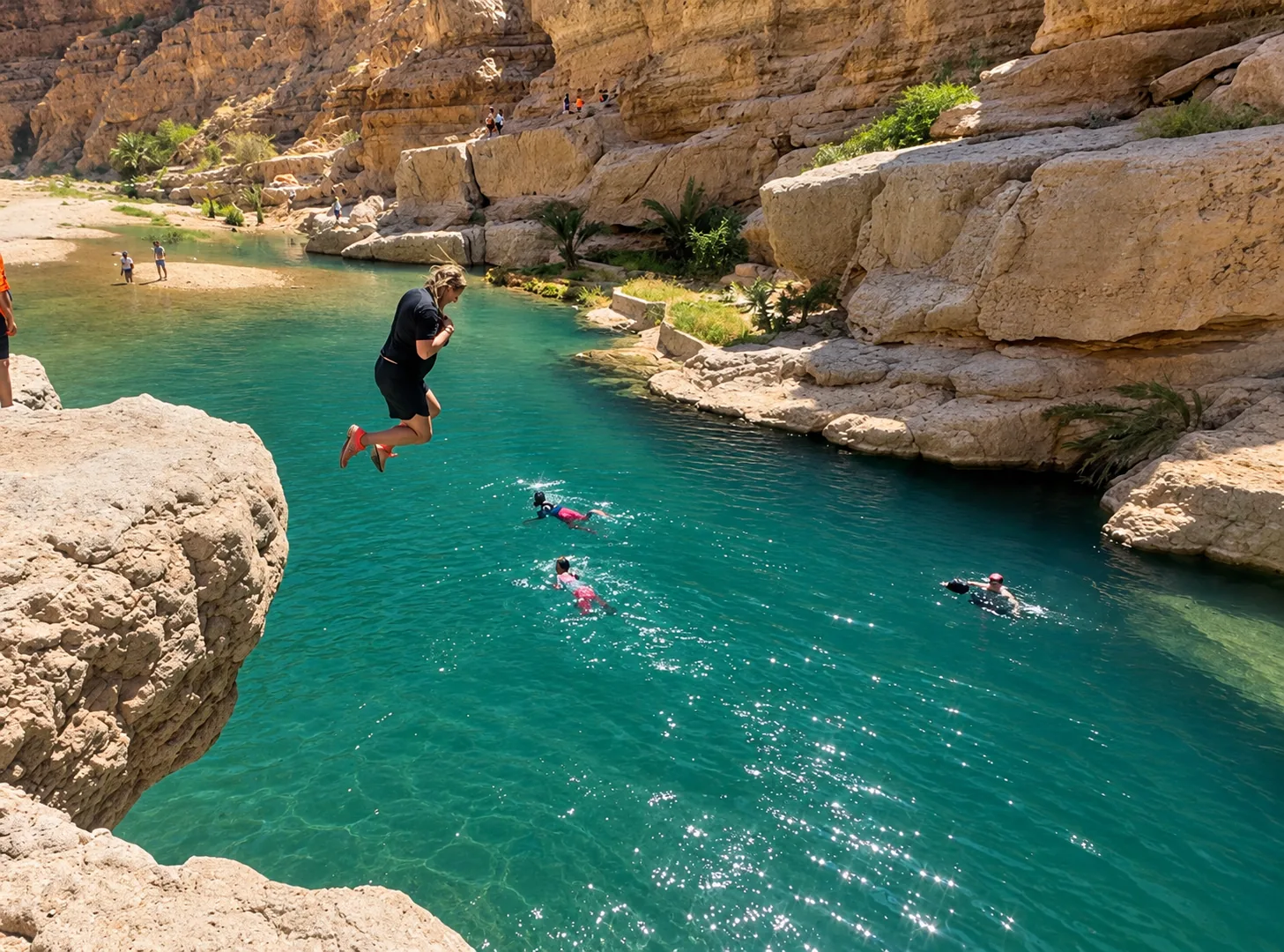 Amy mid-leap off the rocks into the turquoise pool at Wadi Shab
